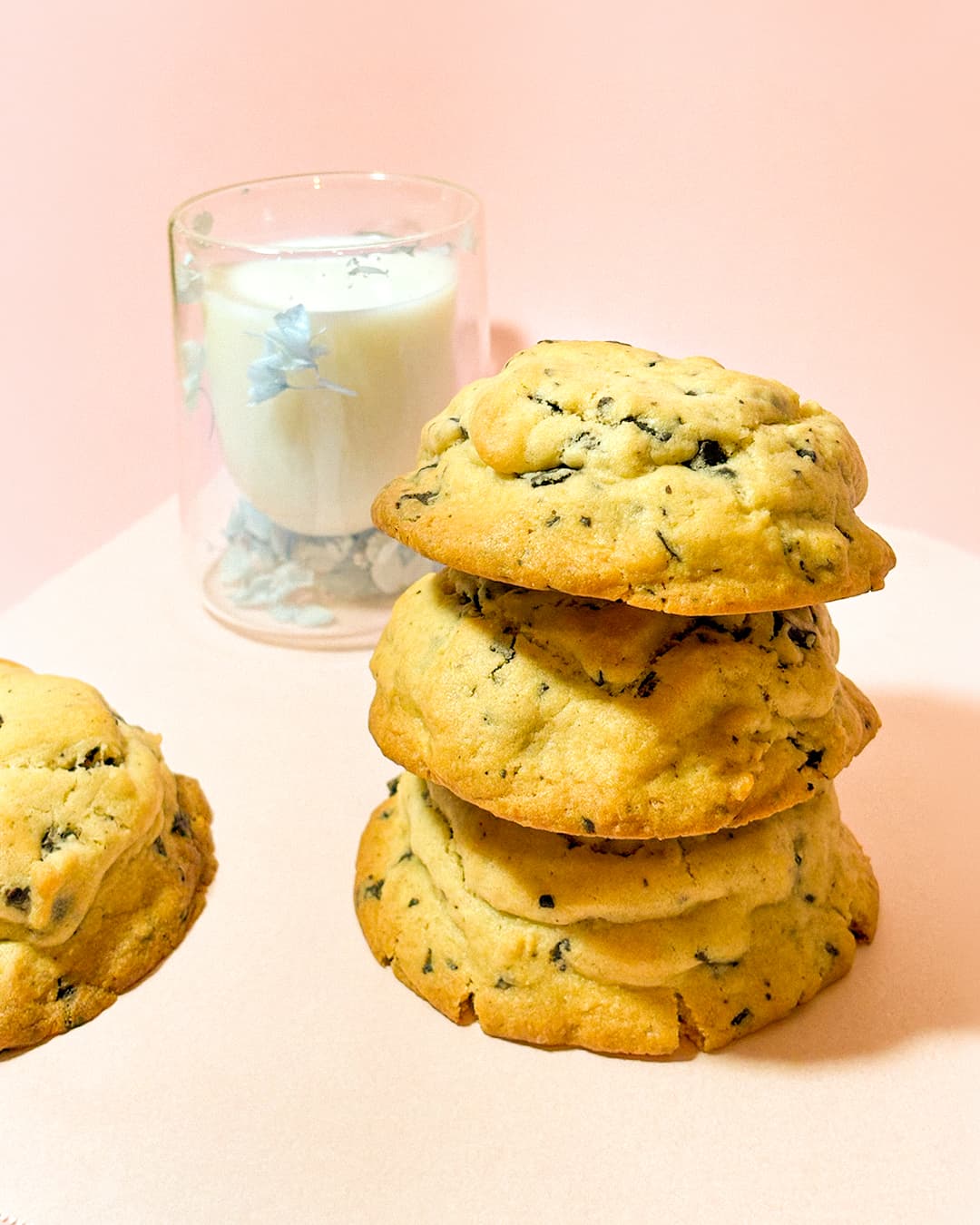 Tres galletas apiladas una sobre otra, de fondo hay una vaso con leche.